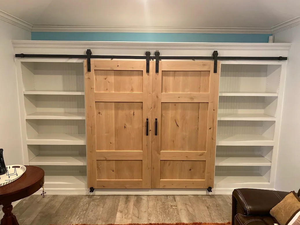 Dual sliding barn doors with white built-in shelving, black hardware and track system