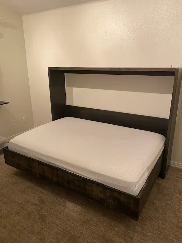 Dark wood bed frame with white mattress and integrated headboard in bedroom